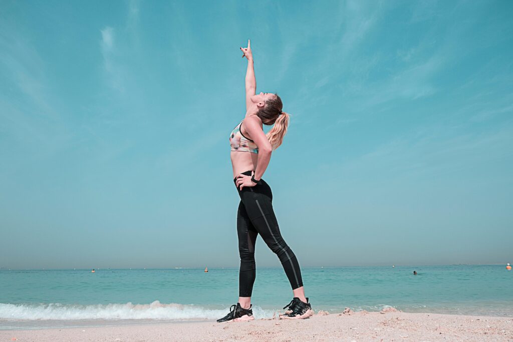 A woman stretching on the beach, symbolizing gentle fitness for beginners in a calm and natural environment.