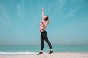 A woman stretching on the beach, symbolizing gentle fitness for beginners in a calm and natural environment.