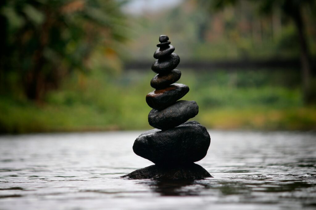 Stacked stones on a beach representing staying consistent with balance and calm.