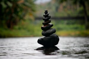 Stacked stones on a beach representing staying consistent with balance and calm.